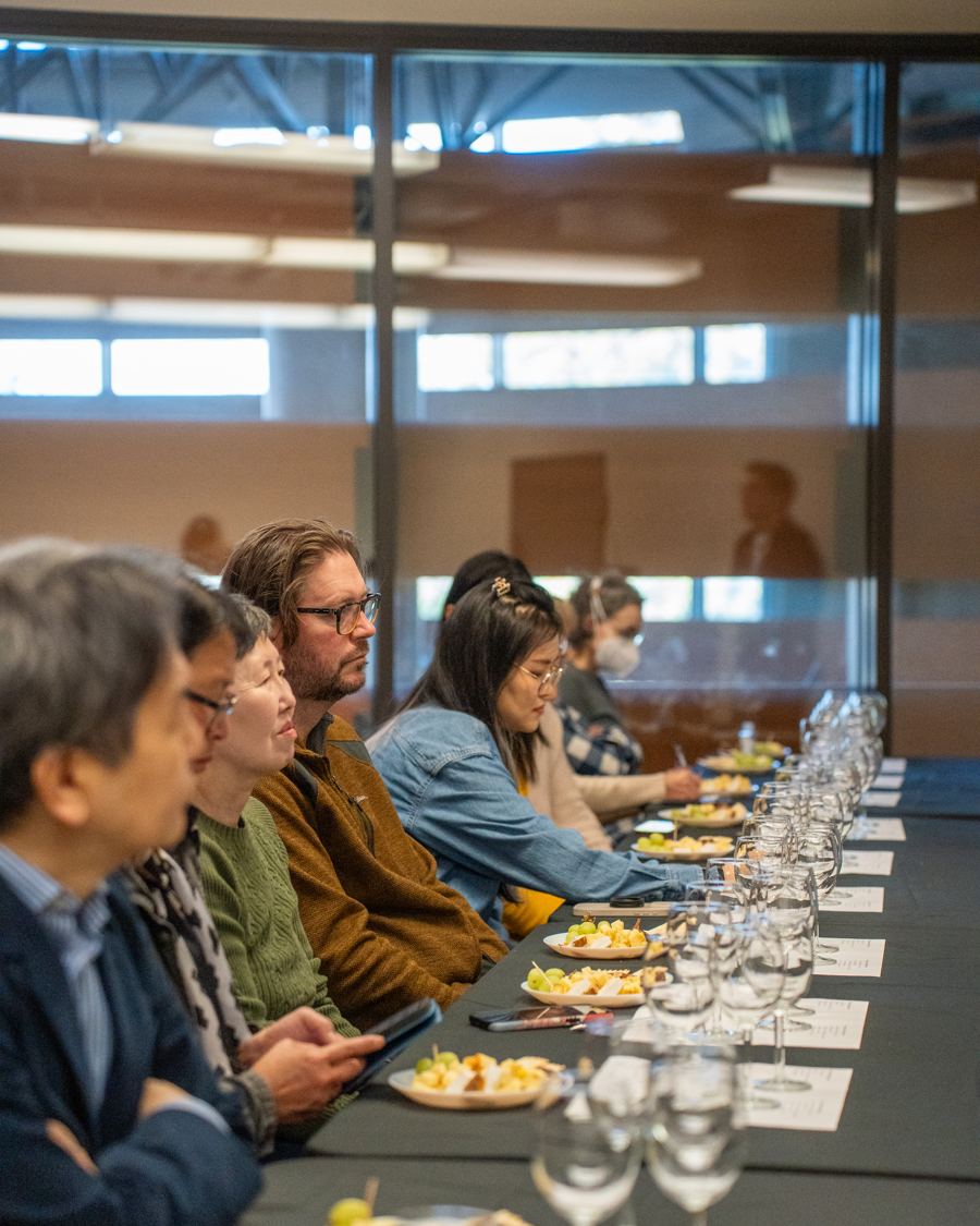 Guests seated along a long table at a tasting event