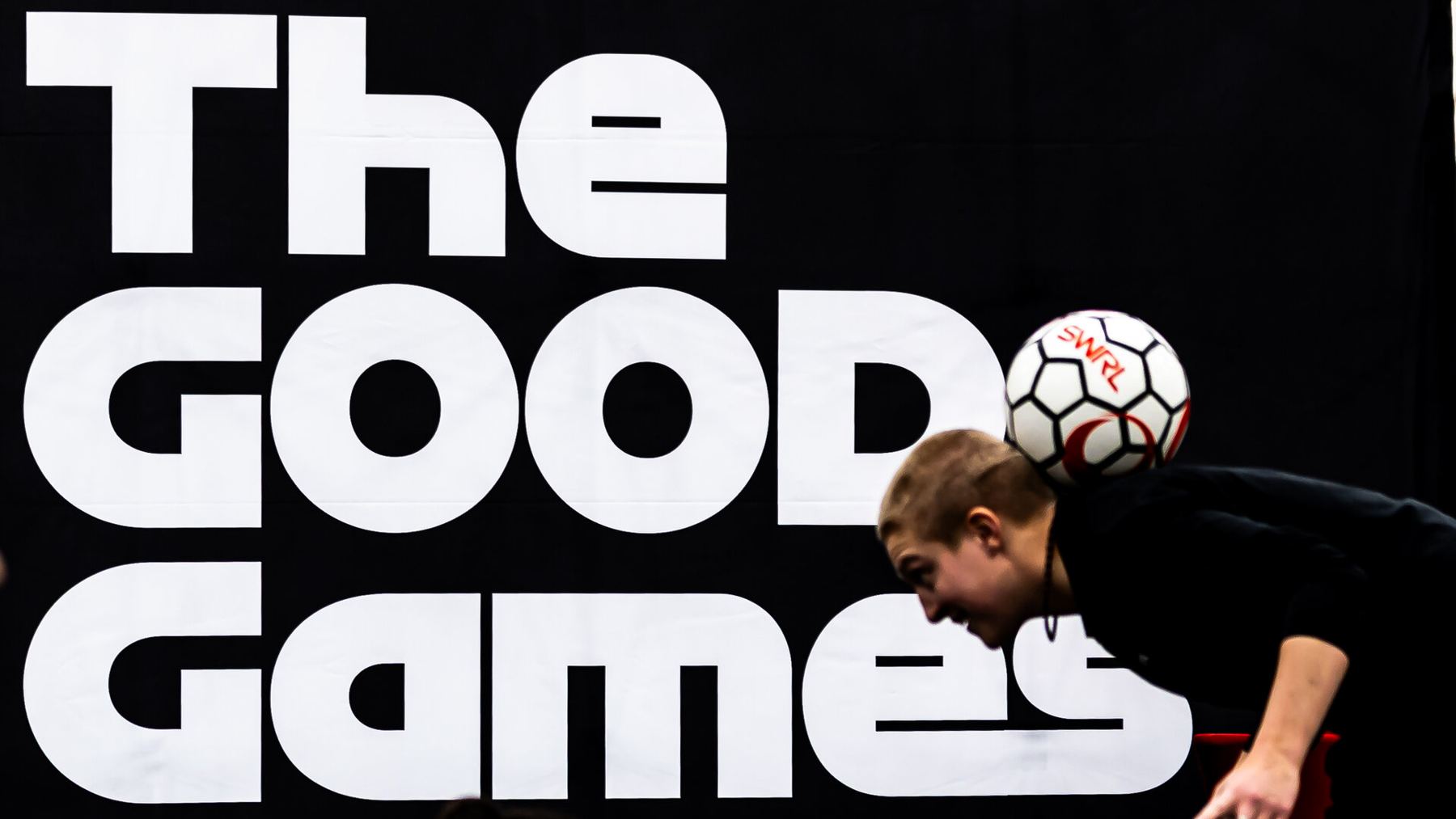 A freestyler balancing a ball on his neck in front of The GOOD Games banner