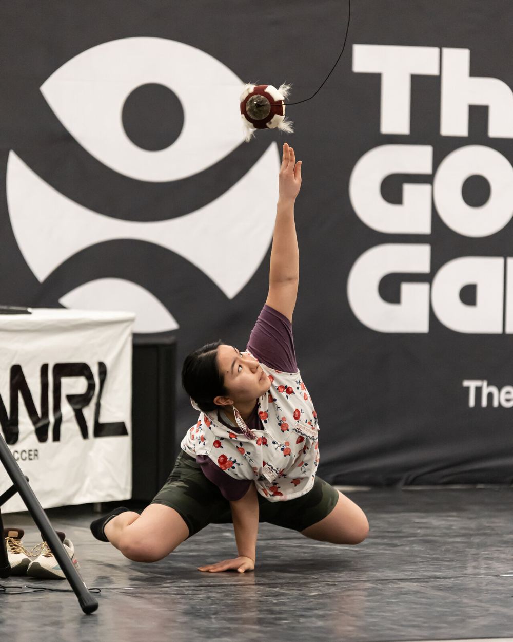 An athlete reaching for a suspended ball during an Indigenous sport demonstration