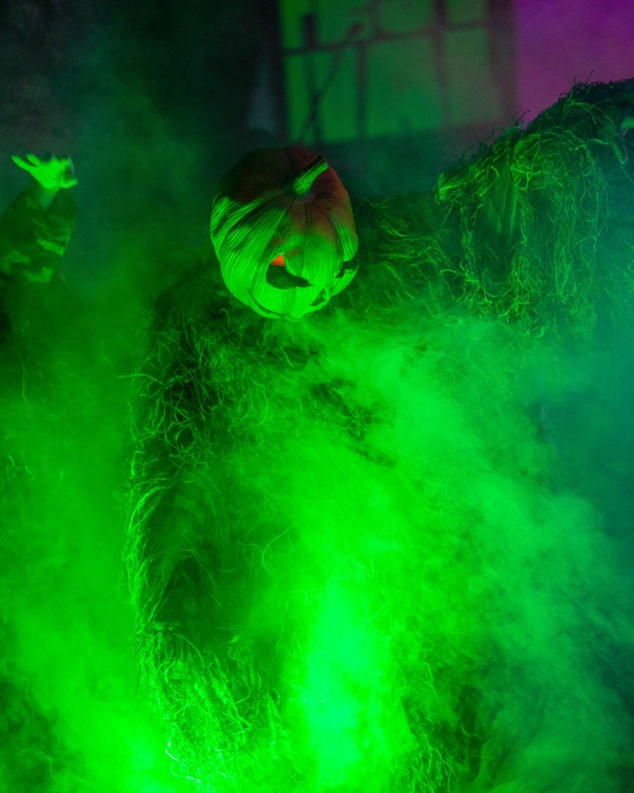 Pumpkin-headed performer in green fog