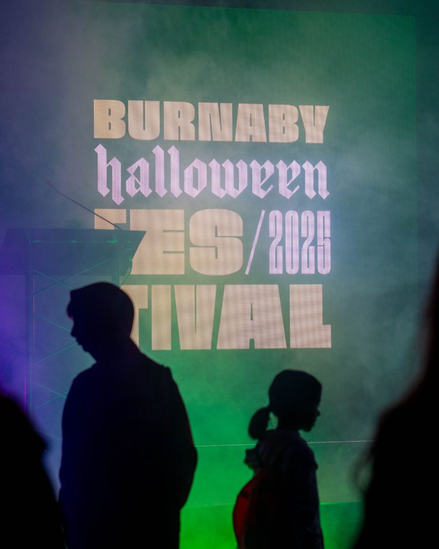 Silhouettes in front of the Burnaby Halloween Festival 2025 screen